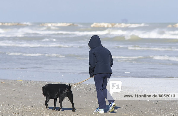 Hooded woman walking dog on beach  Porto San Giorgio  Italy
