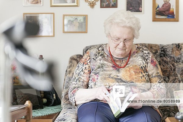 Alte Frau mit Rätselbuch auf der Couch