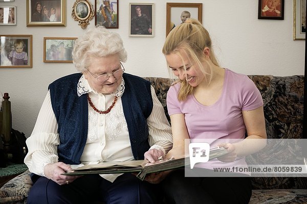 Alte und junge Frau schauen in ein Fotoalbum
