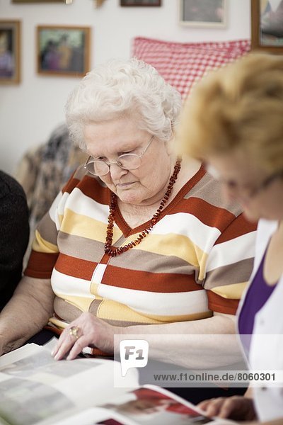 Altenpflegerin und alte Frau schauen in ein Fotoalbum