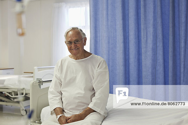 Älterer Patient sitzt auf dem Krankenhausbett