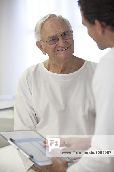 Doctor talking with older patient in hospital room