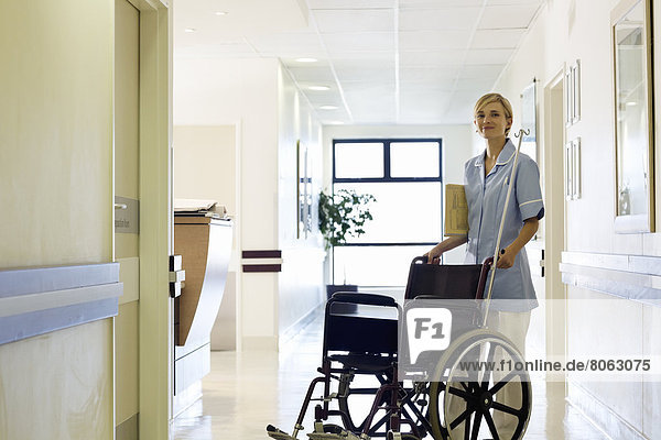 Nurse pushing wheelchair in hospital hallway
