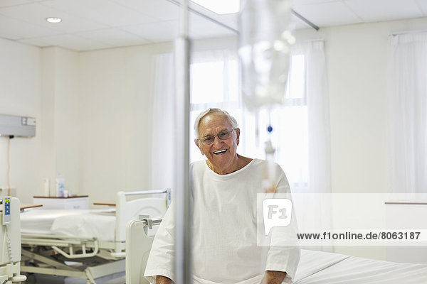 Älterer Patient im Krankenhauszimmer auf dem Bett sitzend