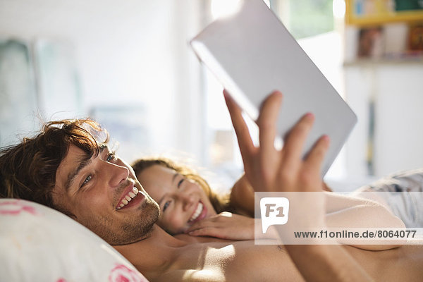 Paar mit Tablet-Computer im Bett