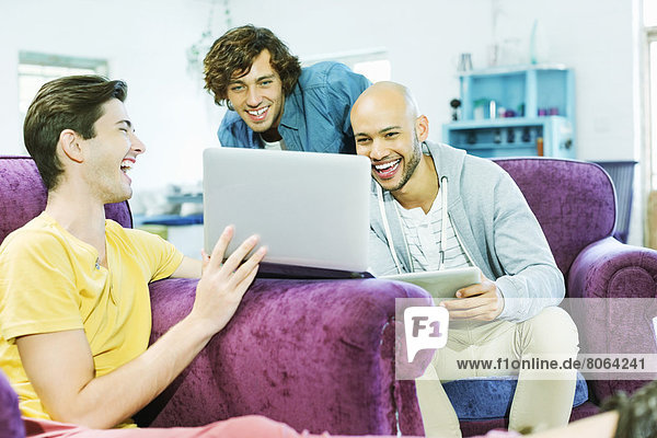 Men using laptop together in living room