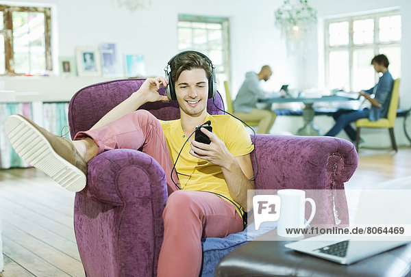 Man listening to headphones in armchair