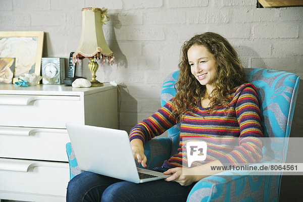 Woman using laptop in armchair