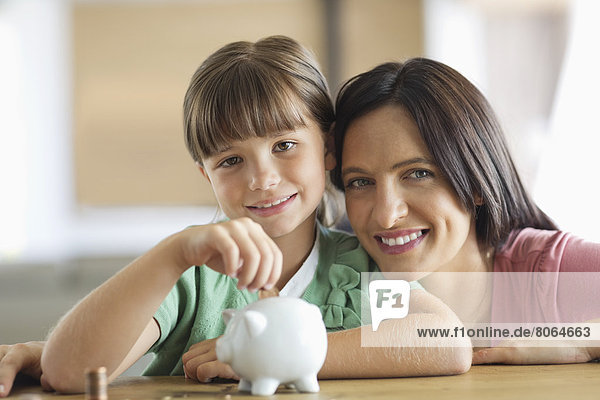 Mother and daughter filling piggy bank