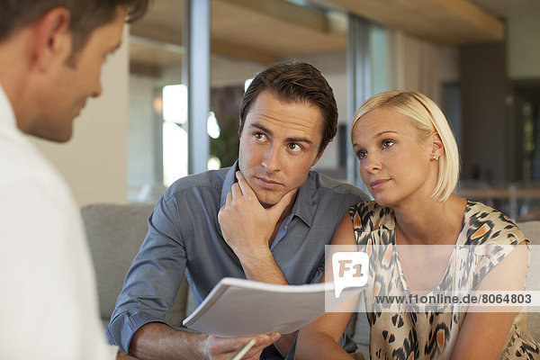 Finanzberater im Gespräch mit einem Paar auf dem Sofa