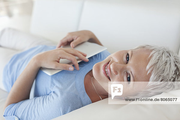 Woman holding tablet computer on sofa