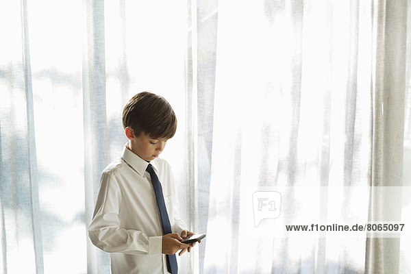 Junge in Hemd und Krawatte mit Handy