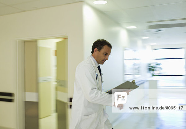 Doctor reading medical chart in hospital hallway