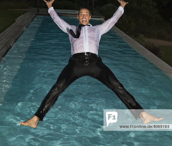 Fully dressed man jumping into swimming pool