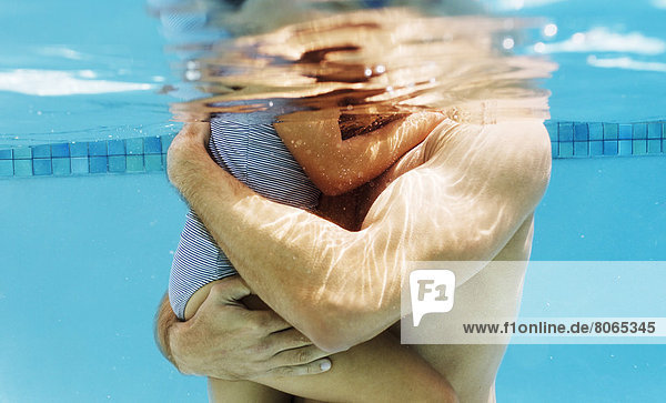 Father holding daughter in swimming pool