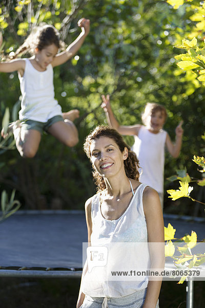 Mutter steht den Kindern auf dem Trampolin zur Seite
