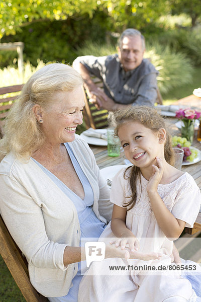 Older woman sitting with granddaughter outdoors