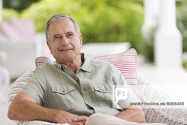 Older man sitting in armchair outdoors