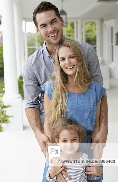 Familie lächelt gemeinsam auf der Veranda