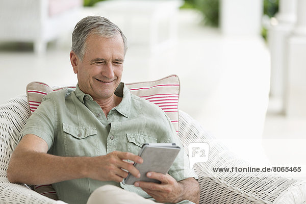 Older man using tablet computer on porch