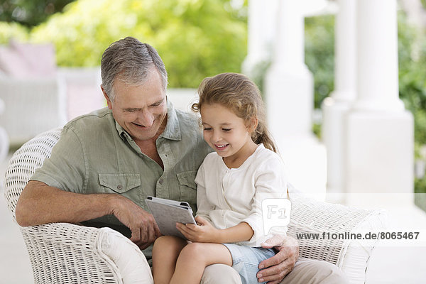Older man and granddaughter using tablet computer