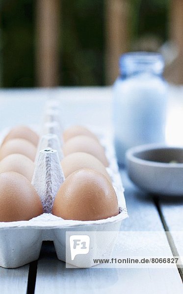 Frische Eier im Karton auf Gartentisch