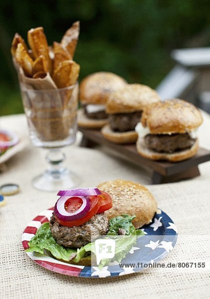Gegrillte Büffel-Burger mit Vollkornbrötchen auf Pappteller mit amerikanischer Fahne