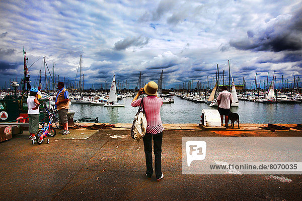 Atmosphere during the summer season in the harbour of Arcachon (Gironde  Aquitaine  France). tourists  a woman taking a picture of her family in front of boats