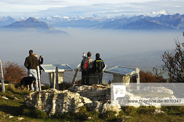 Saleve mountain and Mont Blanc Massif near the arrondissement of Gex  Haute-Savoie department (Upper Savoy)  France. A group of hikers looking at the view and the valley under the fog. Viewpoint indicator  panorama  fog