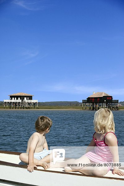 'Two children on a boat  a boy and his sister  looking at the pile dwellings of the island ''ile aux oiseaux'' in the Arcachon bay (Gironde  Aquitaine  France)'