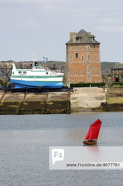 'Small boat with red sail  sailing in front of the ''Tour Doree'' (Golden Tower) or ''Tour Vauban''.'