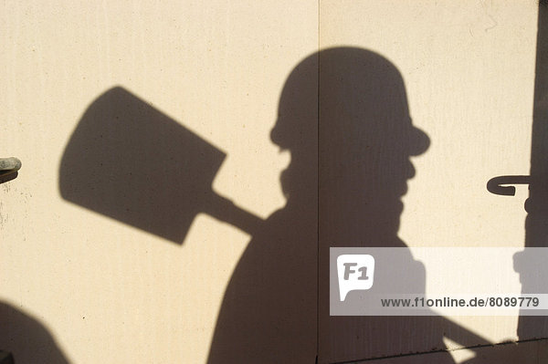 Shadow of a worker with hard hat and spade  symbolic image for black labour  black economy