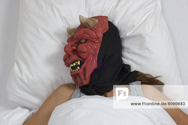 Schlafende Frau mit Teufelsmaske
