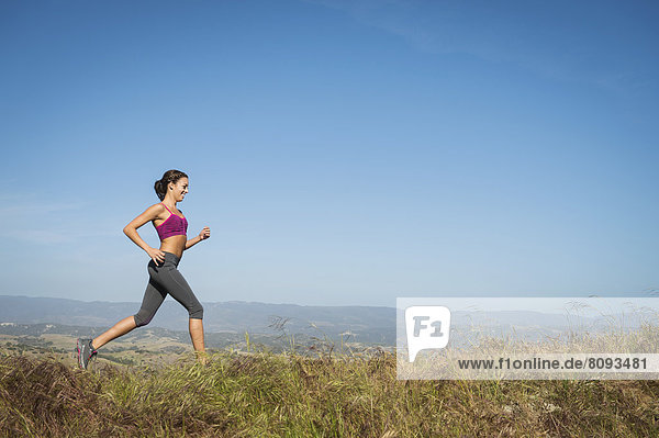 Mixed race woman running in rural landscape