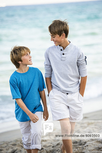 Caucasian boys walking on beach