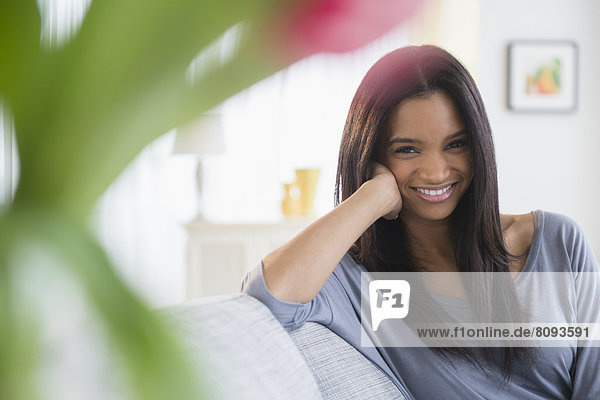 Mixed race woman smiling on sofa