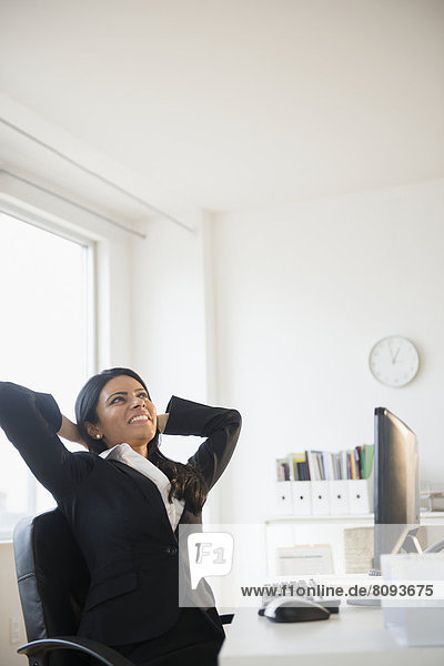 Indian businesswoman stretching at desk
