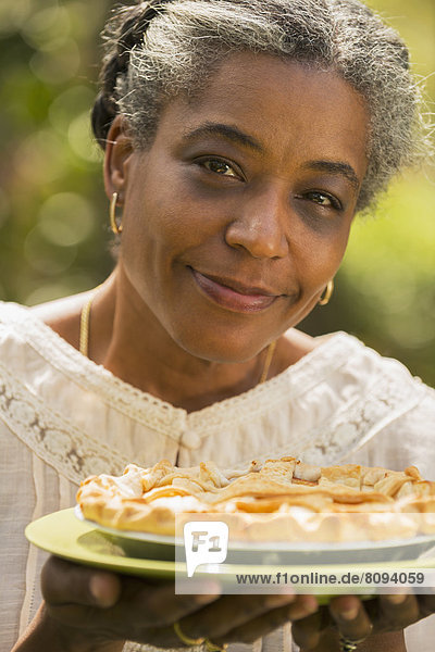 Mixed race woman holding fruit pie outdoors