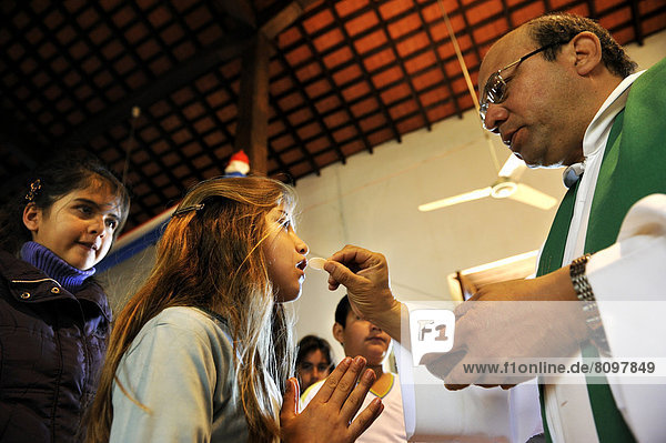 Catholic children's mass  priest giving communion to a girl