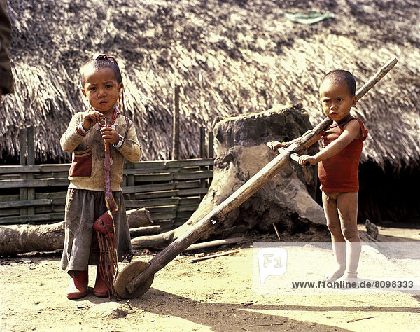 Akha boy and Akha girl in torn clothes with primitive toys  wheel