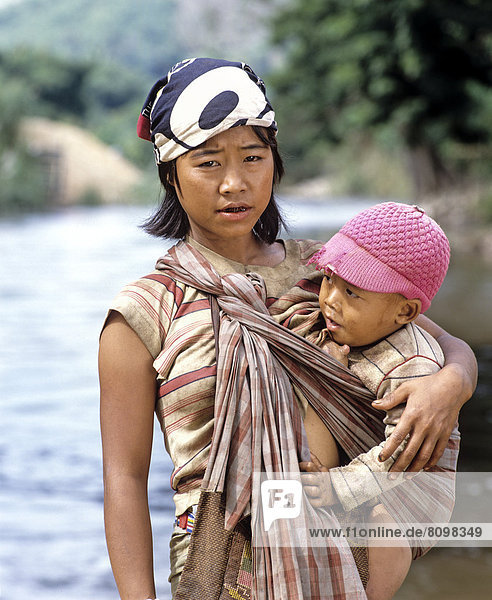 Junge Karen-Frau mit Kind beim Stillen  am Fluss Kok