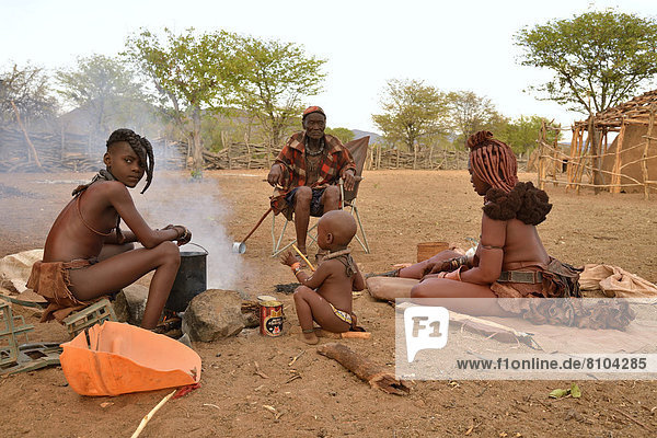 Chief Hikuminue Kapika  der Oberste der namibischen Himba  mit seiner Familie am Feuer in seinem Kral