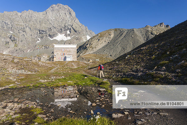 Wanderer an der Berghütte Rifugio Gastaldi  hinten der Berg Uia di Bessanese