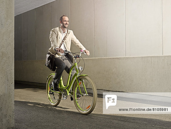 Mann mit Umhängetasche fährt mit Fahrrad durch die Stadt