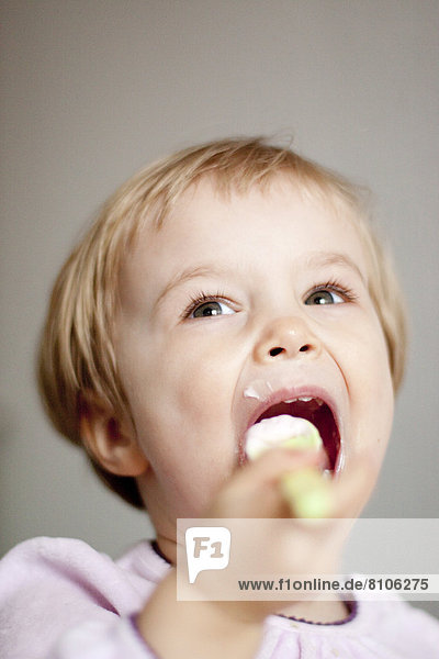 Kleinkind isst einen Joghurt  Portrait