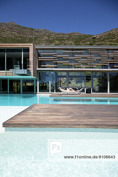 Frau beim Sonnenbaden am Pool des modernen Hauses
