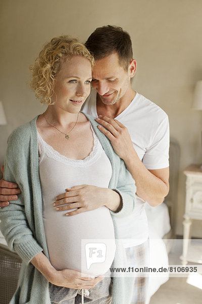 Lächelnder Mann umarmt schwangere Frau