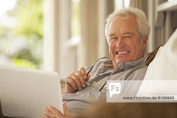 Portrait of smiling senior man using laptop on porch