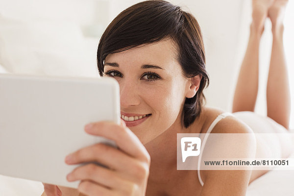 Close up portrait of smiling woman using digital tablet