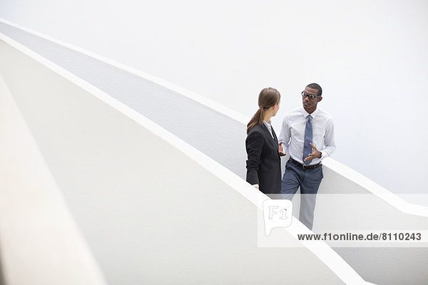 Businessman and businesswoman talking on modern staircase
